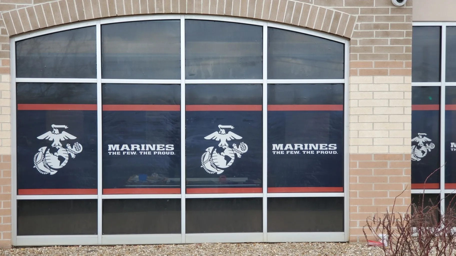 Perforated window graphics with Marines branding on an arched-window facade